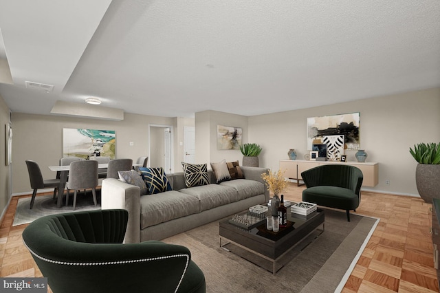 living room featuring a textured ceiling, visible vents, and baseboards