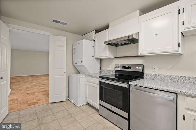 kitchen featuring visible vents, stacked washer / dryer, range hood, stainless steel appliances, and white cabinetry