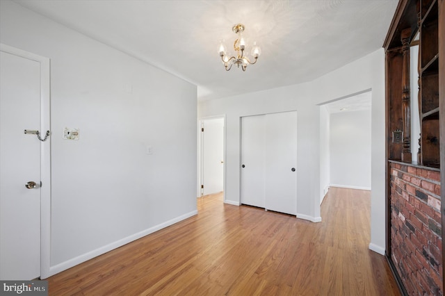 interior space with a chandelier, wood finished floors, and baseboards