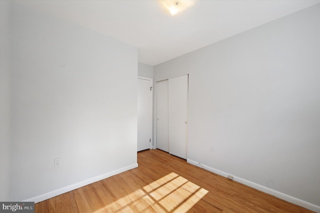 unfurnished bedroom featuring a closet, wood finished floors, and baseboards