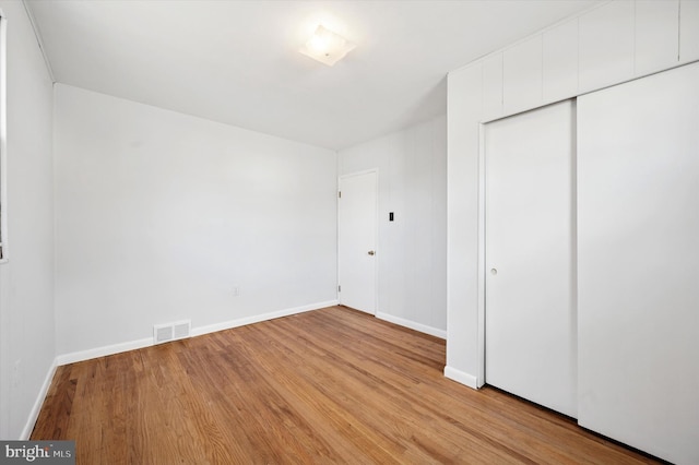 unfurnished bedroom with light wood-style flooring, a closet, visible vents, and baseboards