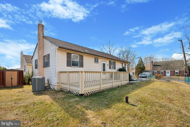 rear view of property featuring a yard, a storage unit, central AC, a deck, and an outdoor structure