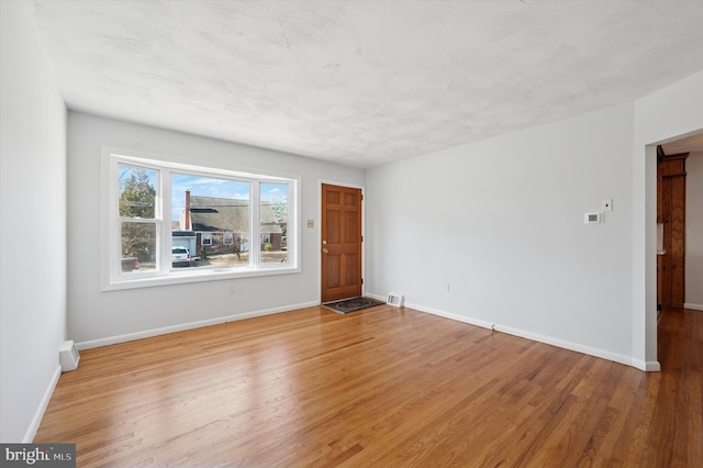 unfurnished room with wood finished floors, visible vents, and baseboards