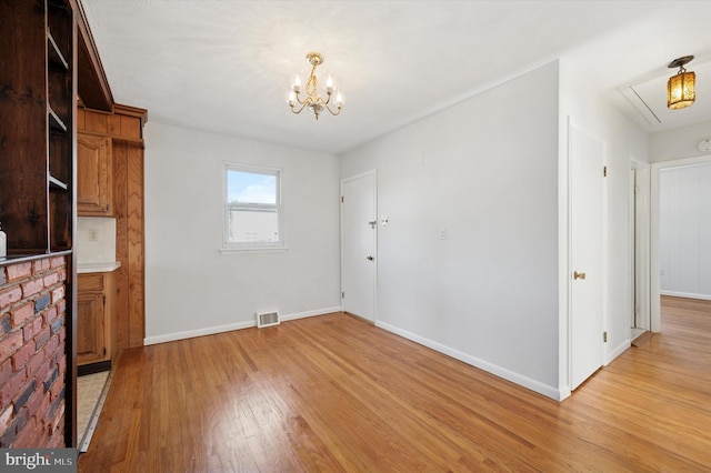 interior space featuring a notable chandelier, visible vents, baseboards, light wood-type flooring, and attic access