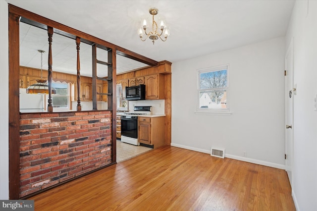 kitchen with visible vents, light wood-style flooring, brown cabinets, black microwave, and gas stove