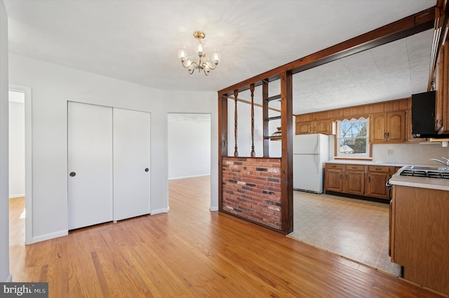 kitchen with light wood finished floors, brown cabinetry, light countertops, and freestanding refrigerator