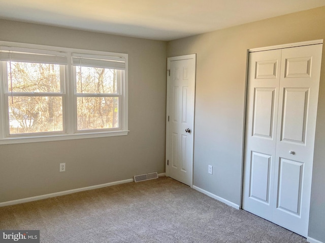 unfurnished bedroom featuring carpet flooring, visible vents, and baseboards