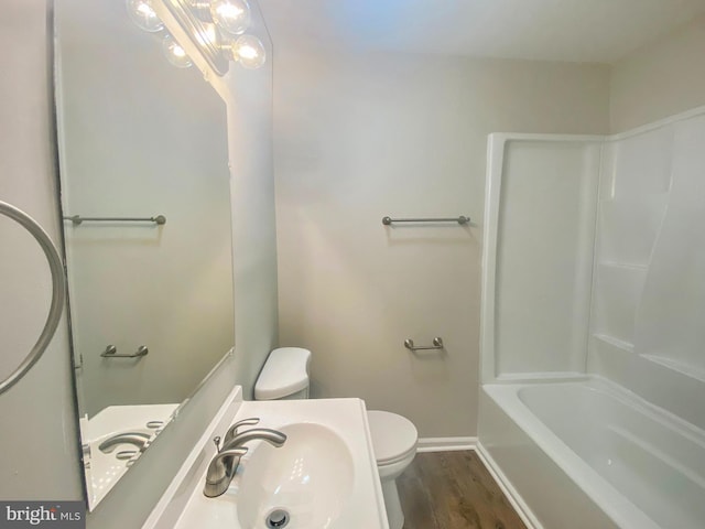 bathroom with toilet, baseboards, a sink, and wood finished floors