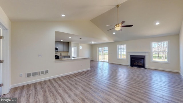 unfurnished living room with recessed lighting, visible vents, light wood-style floors, a sink, and baseboards