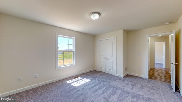 unfurnished bedroom featuring baseboards, a closet, and light colored carpet