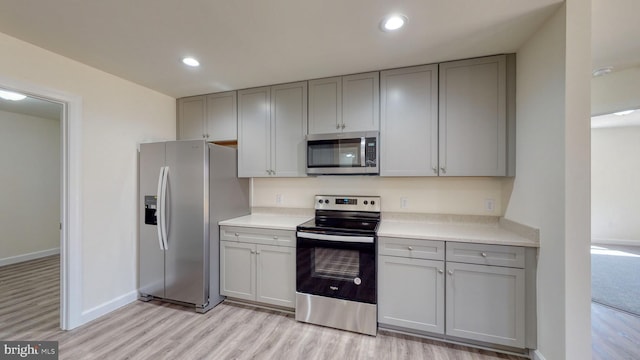 kitchen featuring stainless steel appliances, recessed lighting, light countertops, gray cabinetry, and light wood-style floors