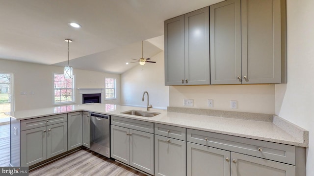 kitchen featuring open floor plan, a peninsula, a sink, gray cabinetry, and stainless steel dishwasher