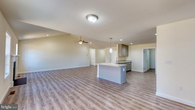 kitchen featuring open floor plan, decorative light fixtures, light countertops, gray cabinetry, and a fireplace