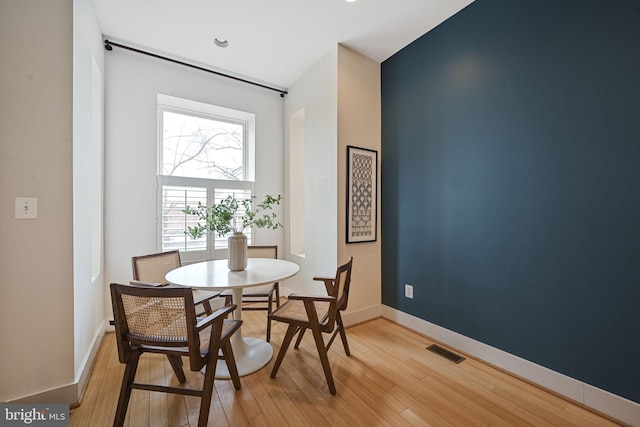 dining room featuring light wood-style floors, visible vents, and baseboards