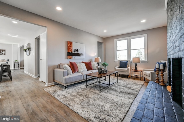 living room with recessed lighting, a fireplace, baseboards, and wood finished floors