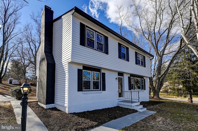 colonial-style house with a chimney and brick siding