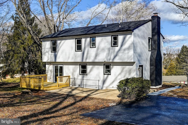 back of house with a deck, a chimney, and a patio area