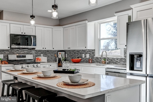 kitchen featuring pendant lighting, stainless steel appliances, a center island, and white cabinets