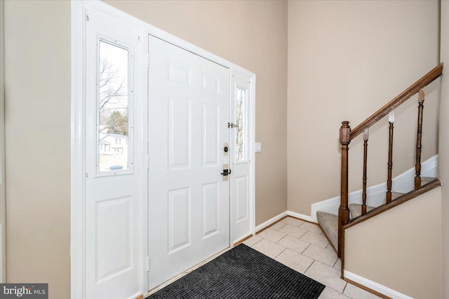 entryway with stairway, baseboards, and light tile patterned floors