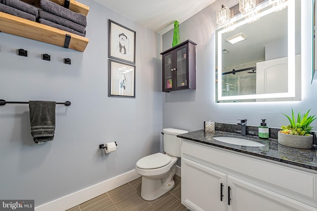 bathroom featuring baseboards, toilet, a shower with shower door, tile patterned floors, and vanity