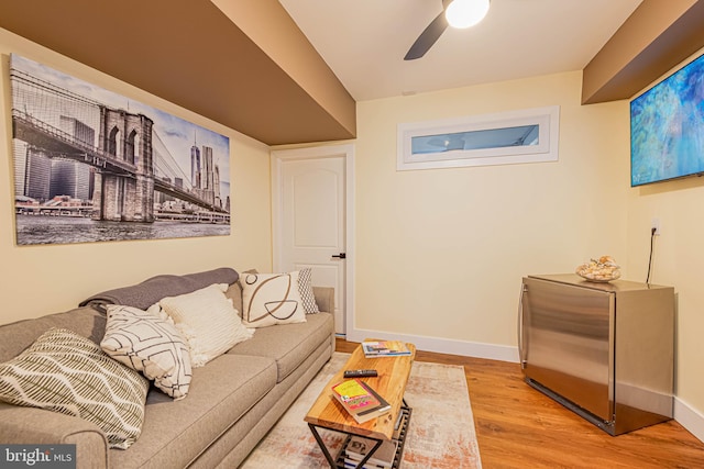 living room featuring ceiling fan, baseboards, and wood finished floors