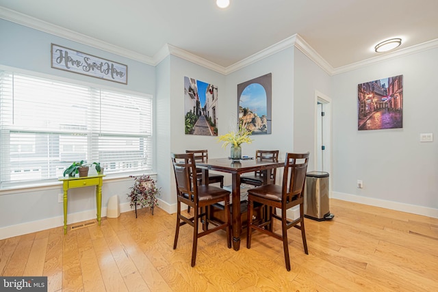 dining space with light wood-type flooring, visible vents, baseboards, and crown molding