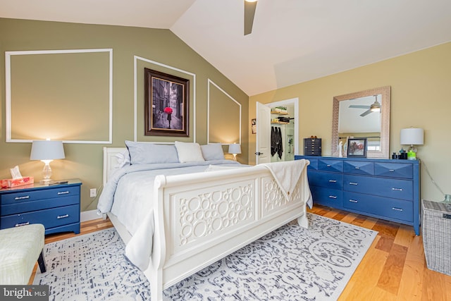 bedroom featuring light wood finished floors, lofted ceiling, a closet, a spacious closet, and ceiling fan