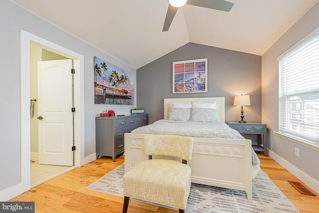 bedroom featuring light wood finished floors, baseboards, visible vents, a ceiling fan, and lofted ceiling