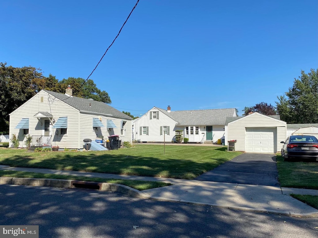 view of front of house featuring an outbuilding, driveway, a front yard, and a garage