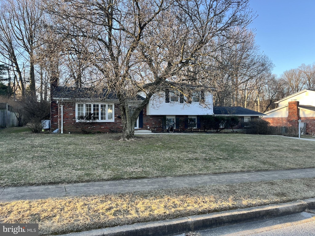 split level home featuring a front yard and brick siding