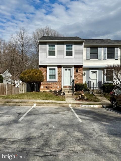 view of front of property with fence, brick siding, and uncovered parking