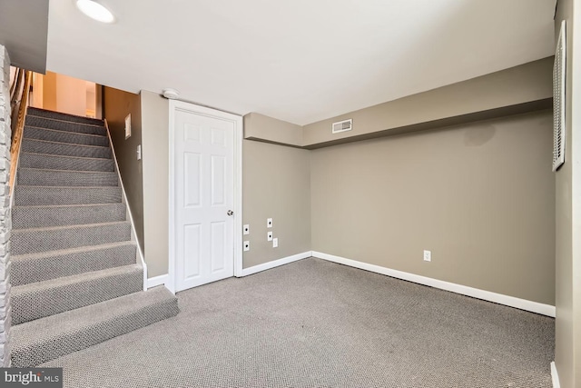 below grade area featuring baseboards, visible vents, carpet flooring, and stairs