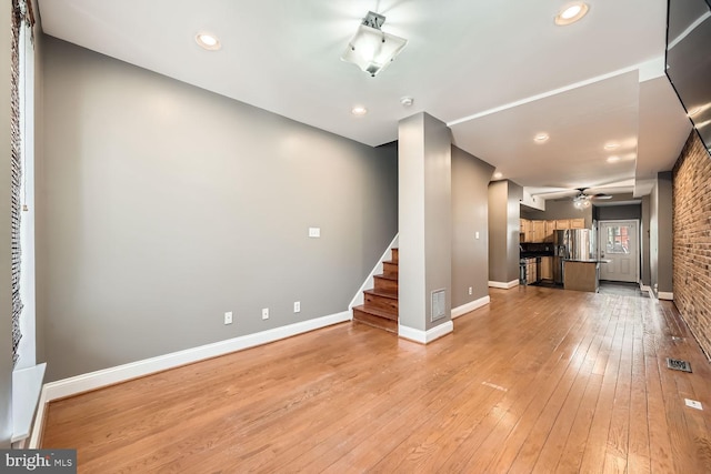 unfurnished living room with light wood-style floors, visible vents, baseboards, and stairs