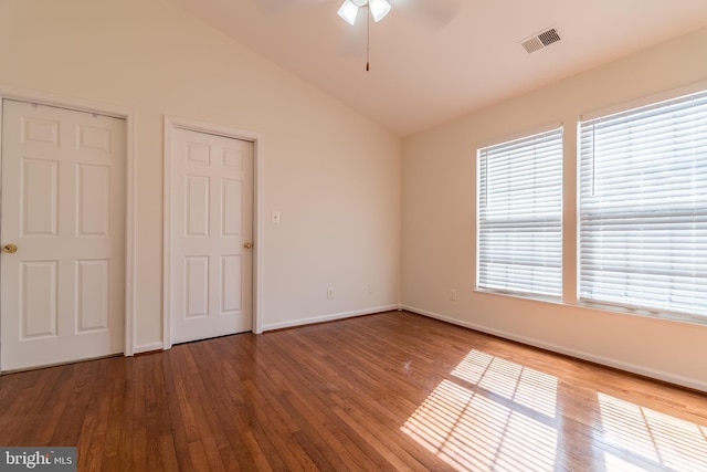 unfurnished bedroom featuring baseboards, visible vents, vaulted ceiling, and wood finished floors