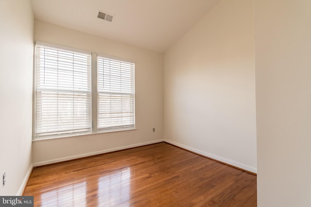 unfurnished room featuring lofted ceiling, wood finished floors, visible vents, and baseboards