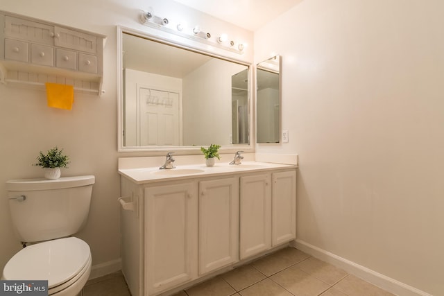 full bath with double vanity, toilet, a sink, tile patterned flooring, and baseboards