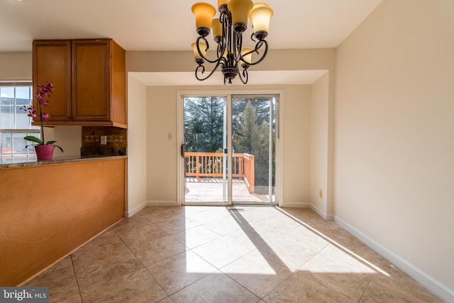 unfurnished dining area with a wealth of natural light, light tile patterned floors, baseboards, and an inviting chandelier