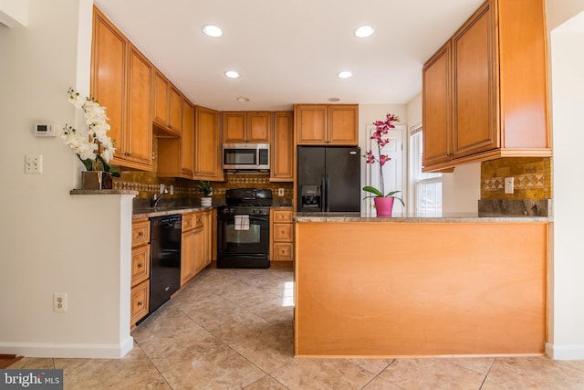 kitchen featuring a peninsula, black appliances, tasteful backsplash, and a sink