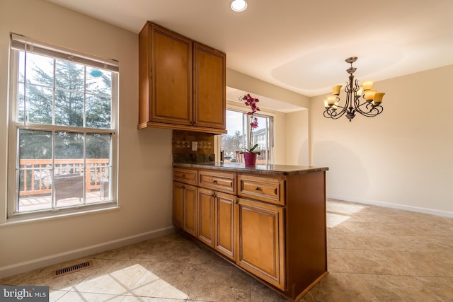 kitchen with decorative light fixtures, visible vents, brown cabinetry, a peninsula, and baseboards