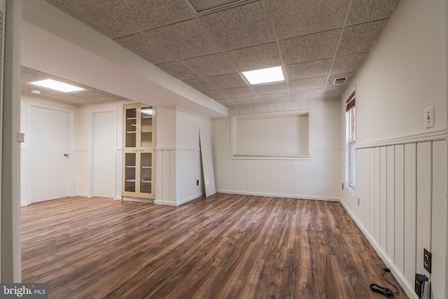 empty room with a paneled ceiling, visible vents, and wood finished floors