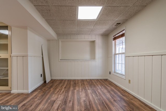 spare room featuring wainscoting, visible vents, a drop ceiling, and wood finished floors