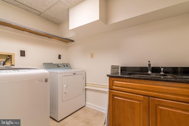 clothes washing area featuring washing machine and dryer, cabinet space, and a sink