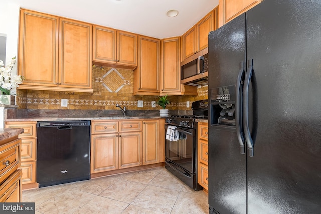 kitchen with light tile patterned floors, decorative backsplash, dark countertops, black appliances, and a sink