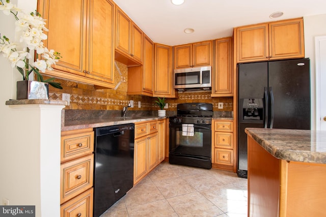 kitchen with light tile patterned flooring, a sink, backsplash, brown cabinets, and black appliances