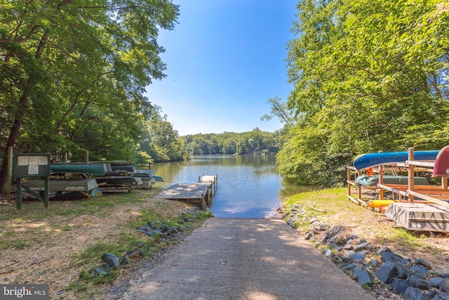 view of dock with a wooded view and a water view