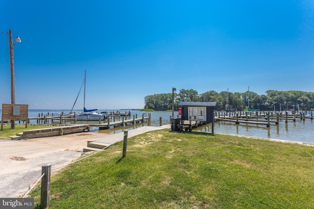 view of dock with a lawn and a water view