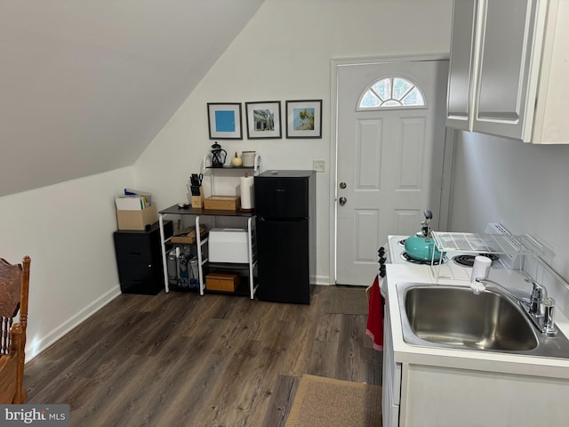 kitchen with vaulted ceiling, white cabinetry, freestanding refrigerator, and dark wood-style flooring