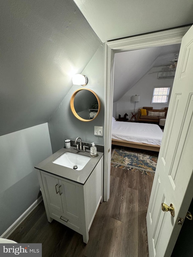 bathroom with baseboards, vanity, lofted ceiling, and wood finished floors