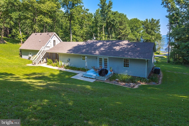 back of property with a yard, cooling unit, french doors, roof with shingles, and a wooden deck