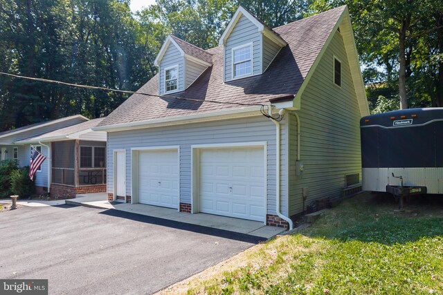 view of property exterior with aphalt driveway, an attached garage, a sunroom, and roof with shingles